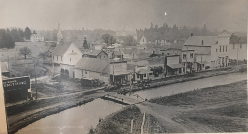 13. 1912 photograph of Turner, with Mill Creek in the foreground and 3rd Street with its row of business buildings behind it. You can see the school building in the upper left-hand corner, and the Turner Tabernacle is faintly visible just right of centre in the background. In those days it still had two towers; now it only has one.