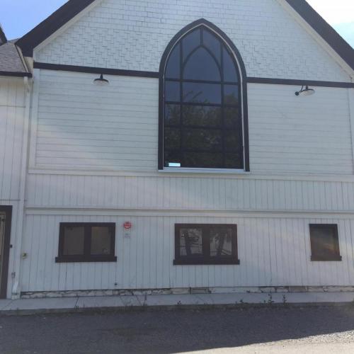 25: Image of a cream-coloured building in shadow, with a large gothic window and three small windows beneath it.